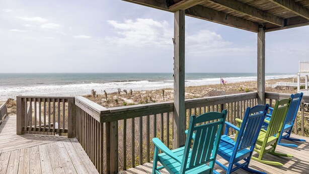 Une terrasse en bois offrant une vue sur la plage et l’océan.