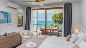 A hotel room with a bed, a desk, a chair, and a view of the ocean.
