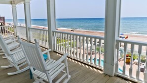 A covered porch with white rocking chairs, a pool, and a view of the beach. - Gone With The Waves, Oceanfront House in Emerald Isle, NC! (Emerald Isle)