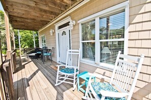 A covered porch with a wooden deck, white rocking chairs, and a small table with chairs. - Grace Appearing, Oceanside House in Emerald Isle, NC! (Emerald Isle)