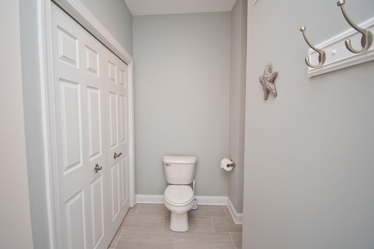 Une salle de bain avec des toilettes, une porte blanche et une étagère murale dotée de crochets.