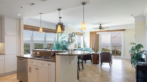 Une cuisine spacieuse dotée d’un grand îlot central, d’un coin repas avec vue et d’un ventilateur de plafond.