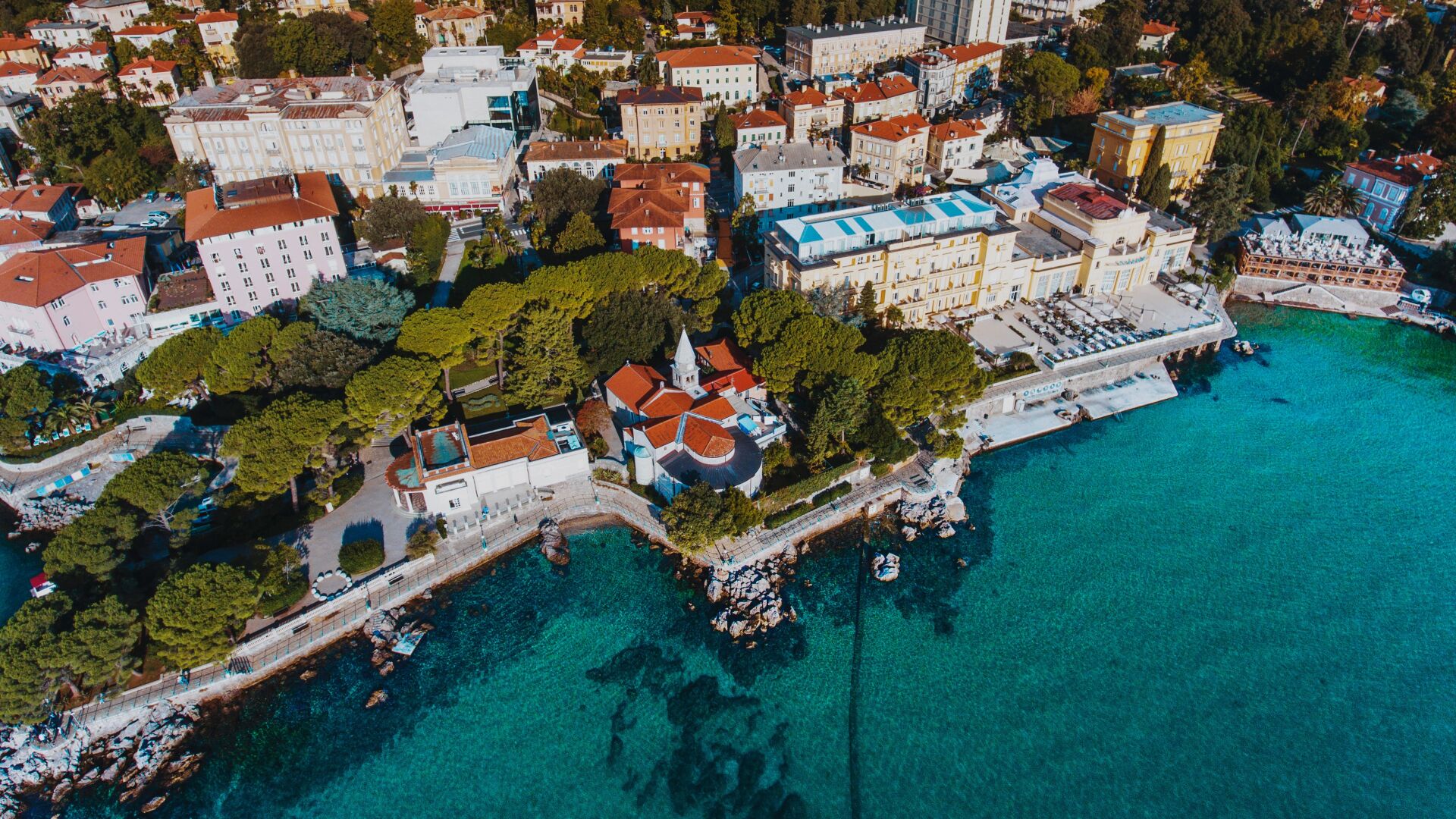 An aerial view of a coastal town with buildings, a church, and a marina.