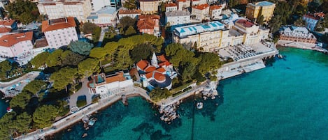 An aerial view of a coastal town with buildings, a church, and a marina.