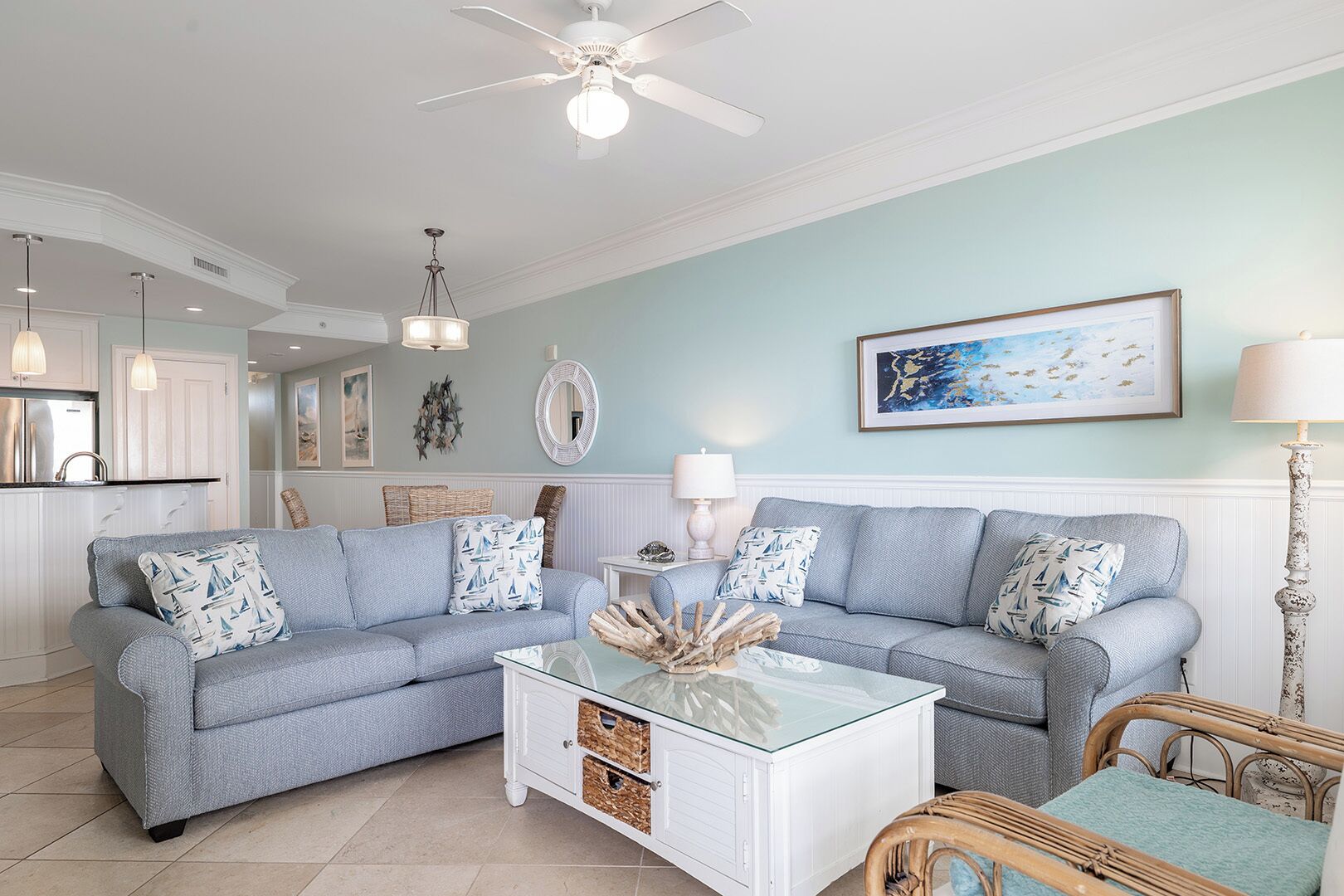 A living room with a light blue sofa, a glass coffee table, and a wicker chair.