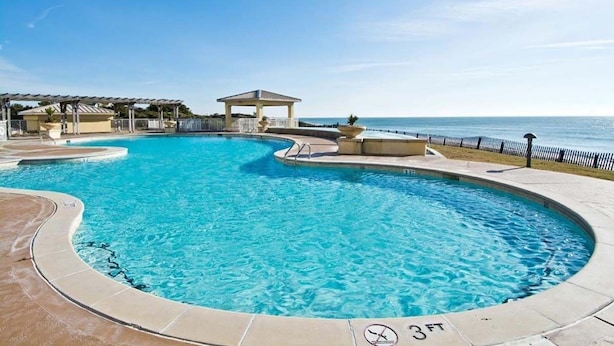 A circular pool with a 3ft depth marker, surrounded by a deck with a gazebo and lounge chairs. - Grande Villas D-3, Oceanfront Condo in Indian Beach, NC! (Indian Beach)