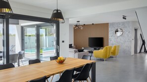 Un espace repas moderne avec une table en bois, des chaises noires et un saladier rempli de fruits.