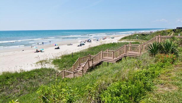 Une plage avec des passerelles en bois menant au rivage, une plage de sable et l’océan.