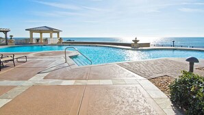 Un espace piscine agrémenté d’un gazebo, de chaises longues et offrant une vue sur l’océan.