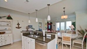 A spacious kitchen with a central island, white cabinetry, and pendant lighting. - Grande Villas M-3, Oceanfront Condo in Indian Beach, NC! (Indian Beach)