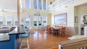 A spacious dining area with a high ceiling, large windows, and a view of the ocean. - Grandview, Oceanfront House in Emerald Isle, NC! (Emerald Isle)