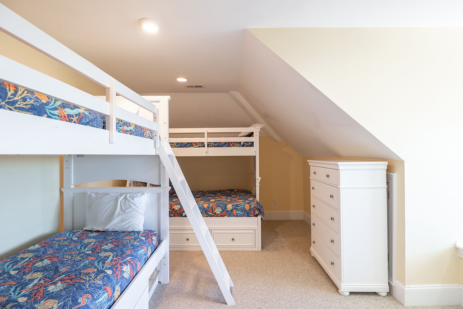 A room with bunk beds, a dresser, and a ladder.