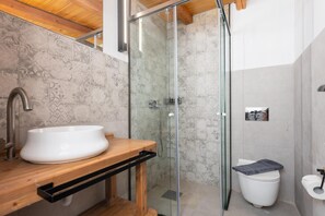 Un baño moderno con lavamanos independiente, cabina de ducha de vidrio y un inodoro.