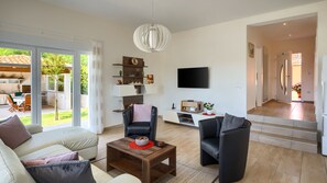A modern living room with a sofa, chairs, a coffee table, a TV, and a fireplace.