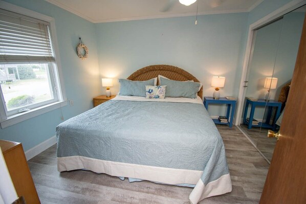 Une chambre à coucher avec un grand lit, deux tables de chevet, une fenêtre et une porte.