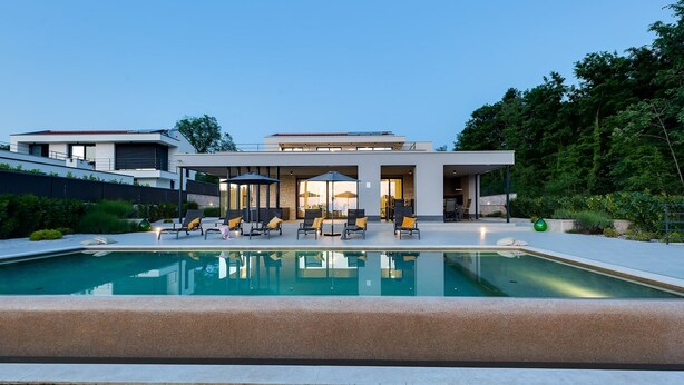Una casa moderna con piscina, mobiliario exterior y un jardín bien cuidado.