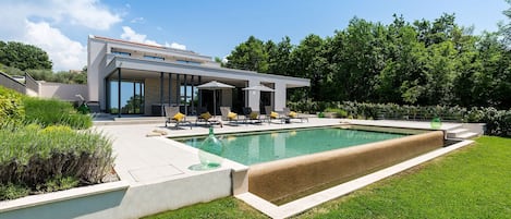 A modern house with a swimming pool, outdoor seating, and a well-maintained garden.