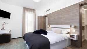 Un dormitorio moderno con cama, mesitas de noche, escritorio, televisor y armario.