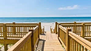 A wooden boardwalk leading to a sandy beach with the ocean in the background. - Tides Out West, Oceanfront Duplex in Emerald Isle, NC! (Emerald Isle)