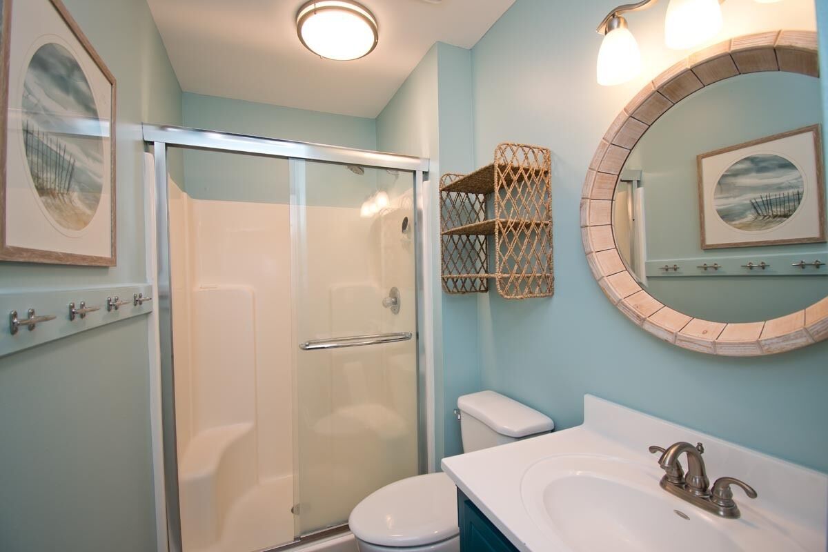 Une salle de bain avec une douche à parois de verre, des toilettes et un lavabo avec un miroir au-dessus.