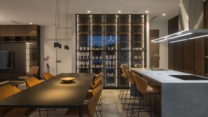 Una cocina moderna con una isla central, taburetes de bar y una vinera empotrada.