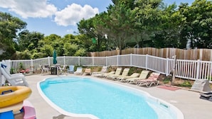 A backyard with a swimming pool, lounge chairs, and a wooden fence. - Tranquillis East, Almost Oceanfront Duplex in Emerald Isle, NC! (Emerald Isle)