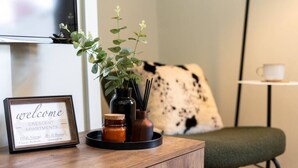Une pancarte d’accueil pour l’immeuble Crescent Apartments, une petite table avec une plante, des bougies et une tasse.