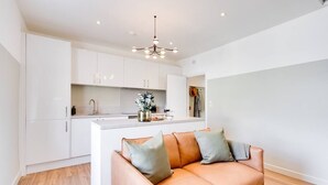 Une cuisine moderne avec des meubles blancs, un îlot central et un luminaire suspendu.