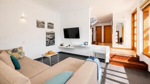 Een moderne woonkamer met een bank, een salontafel, een flatscreen televisie en kunstwerken aan de muren.