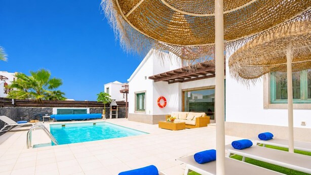 Uma área de piscina com espreguiçadeiras, churrasqueira e um espaço coberto para relaxar.