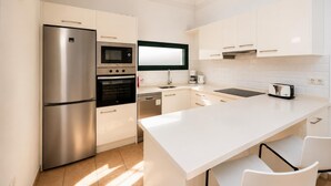 Uma cozinha moderna com eletrodomésticos de aço inoxidável, armários brancos e uma ilha grande com assentos.