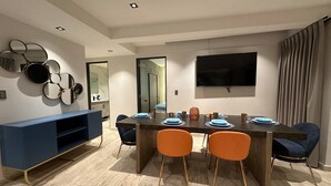 Un'area pranzo moderna con un tavolo di legno, piatti blu e sedie arancioni.