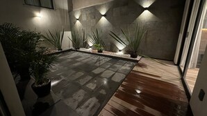 Una moderna zona patio esterna con pavimento in cemento, piante in vaso e un rivestimento in legno.