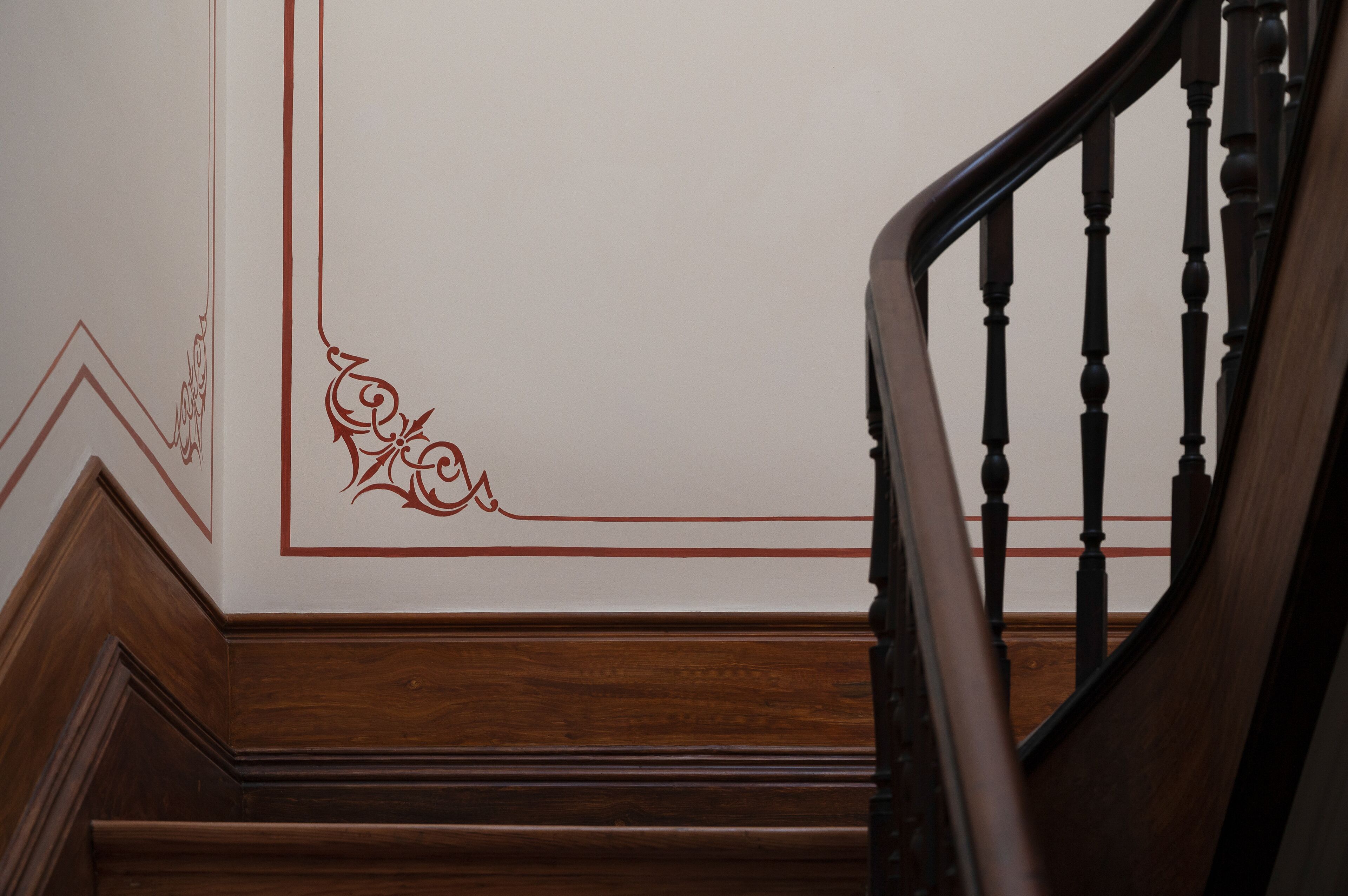 A wooden staircase with a handrail and a wall with decorative trim and a geometric pattern.
