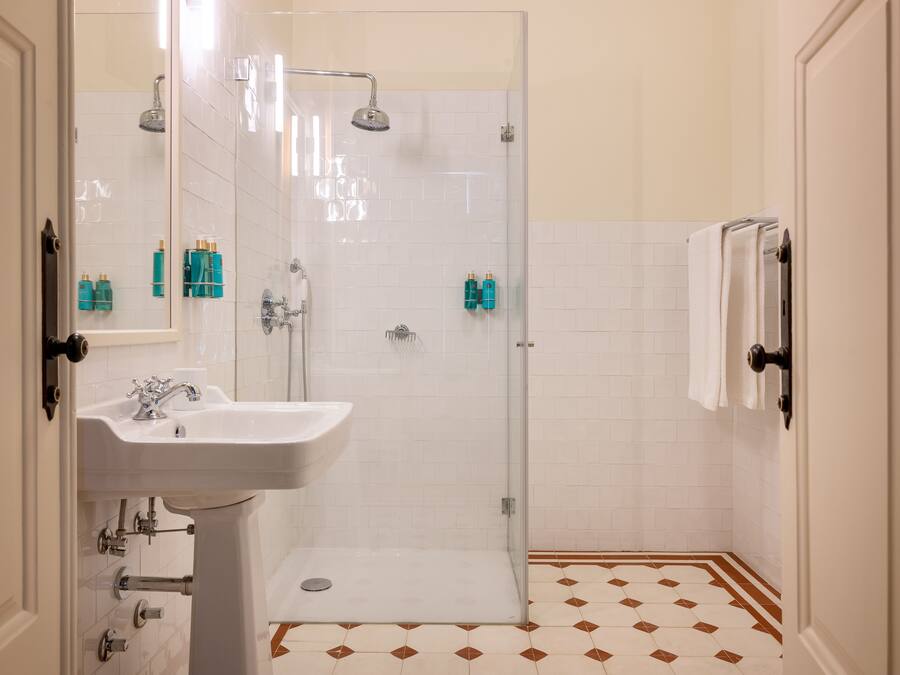 A bathroom with a white sink, a glass-enclosed shower, and a tiled floor with a diamond pattern.