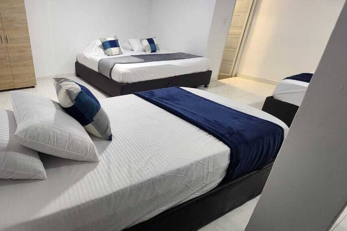 Ein modernes Schlafzimmer mit zwei Betten, jeweils mit weißer Bettwäsche und blauen Akzenten.