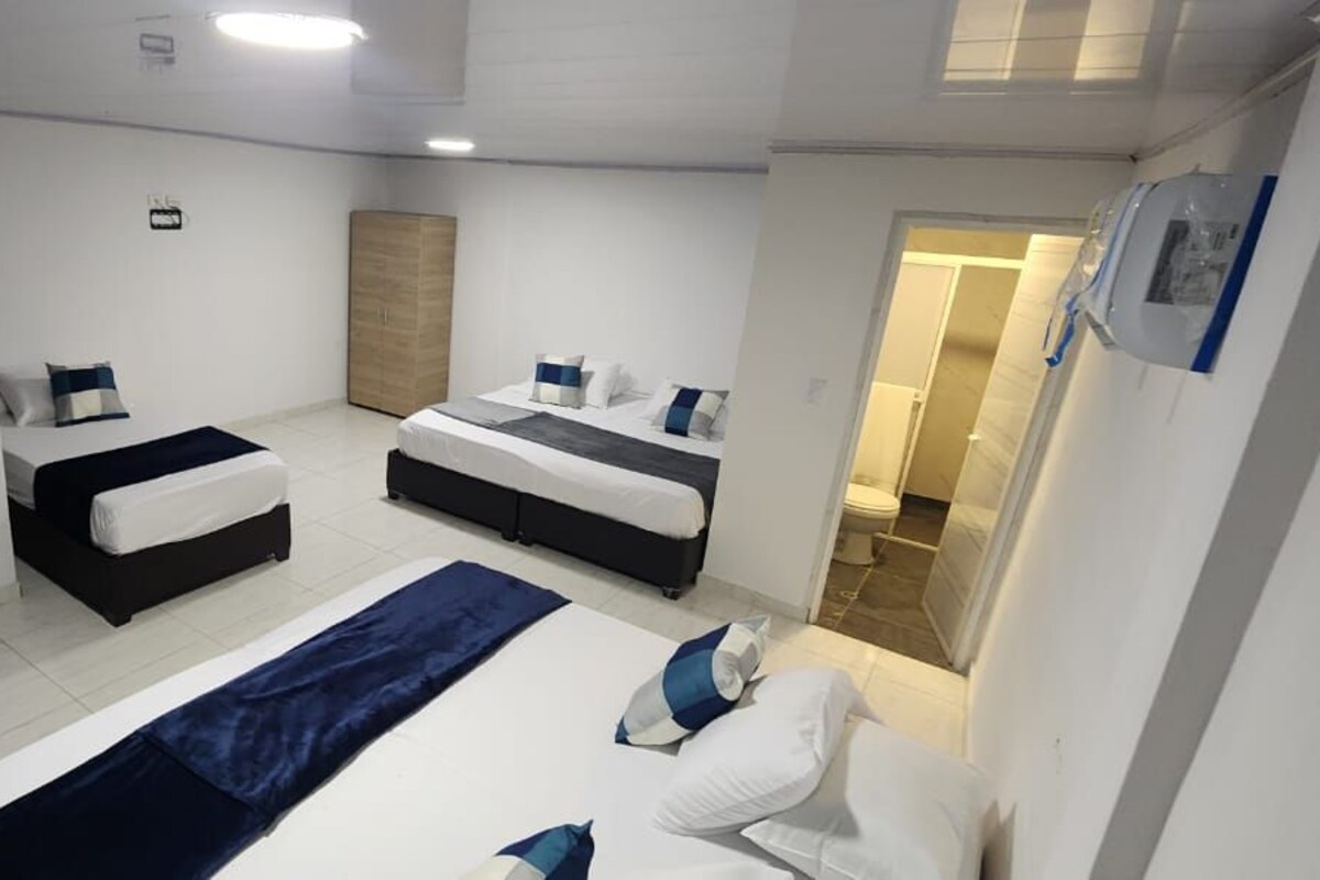 Quarto de hotel com duas camas, uma janela grande e um guarda-roupa.