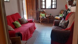 A living room with a red sofa, a wooden chair, and a small table. - Casa Aconchegante em São Sebastião, Próxima ao Centro, Praias e Comércios (São Sebastião)