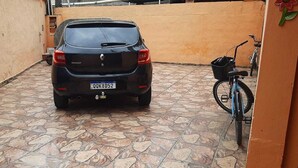 A black Renault car parked in a tiled courtyard with a bicycle and a flower decoration on the wall. - Casa Aconchegante em São Sebastião, Próxima ao Centro, Praias e Comércios (São Sebastião)