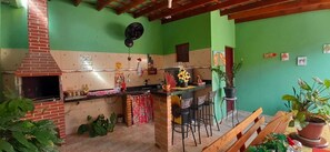 A kitchen with a brick stove, bar stools, and potted plants. - Casa Aconchegante em São Sebastião, Próxima ao Centro, Praias e Comércios (São Sebastião)