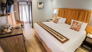 Ein Hotelzimmer mit einem großen Bett, einem hölzernen Kopfteil, einem Nachttisch und einem Schreibtisch mit Frühstücksgebäck.