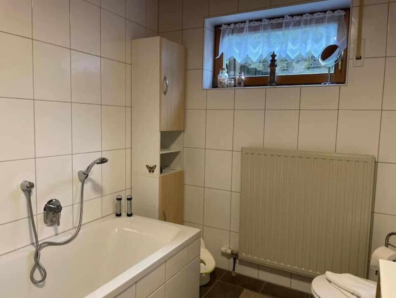 Ein Badezimmer mit Badewanne, einem Fenster mit Aussicht und einer Heizung.