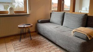 A living room with a grey sofa, a small round table, and a beige rug. - Appartio-60m2-6 Pers-netflix (Hofheim in Unterfranken)
