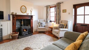 A cozy living room with a fireplace, two armchairs, a sofa, and a television.