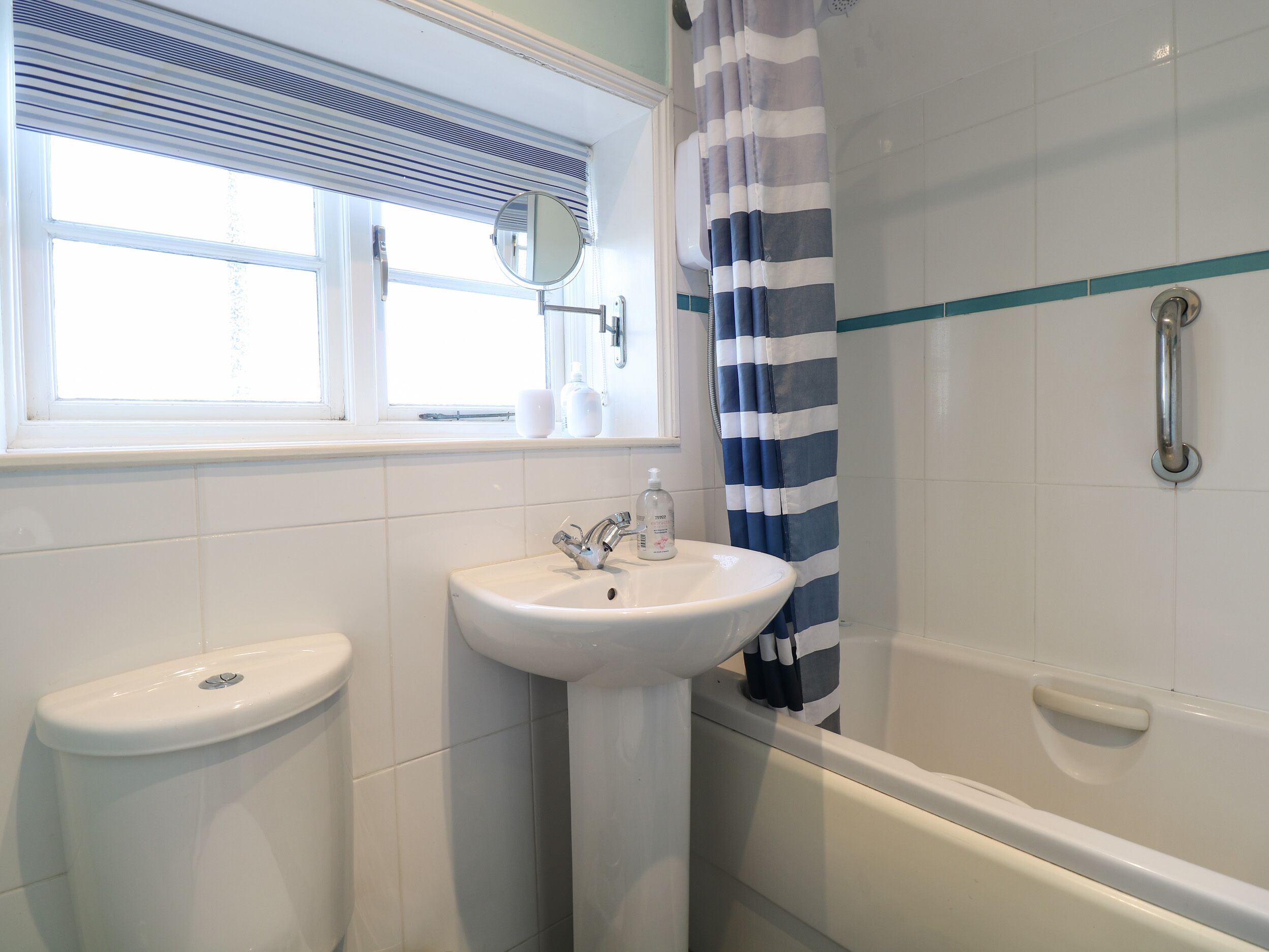 A bathroom with a window, a sink, a toilet, and a bathtub.