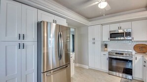 A kitchen with white cabinets, stainless steel appliances, and a tiled floor. - 18116 Cutlass Cozy Pet Friendly Canalfront Home (Fort Myers Beach)