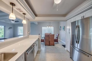 A modern kitchen with a large island, stainless steel appliances, and pendant lighting. - 18116 Cutlass Cozy Pet Friendly Canalfront Home (Fort Myers Beach)