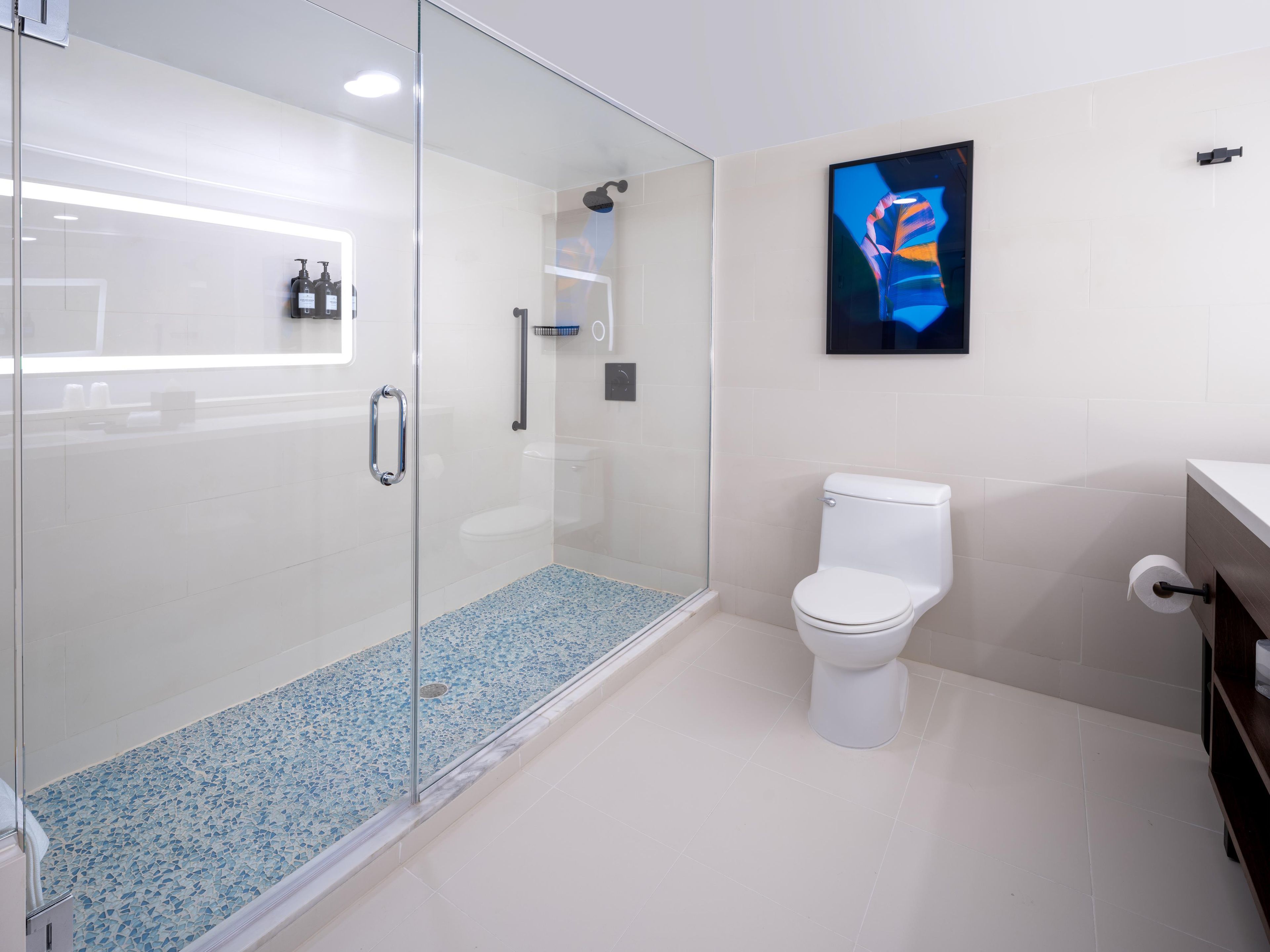 A modern bathroom with a glass-enclosed shower, a toilet, and a sink area.