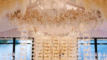 Un espacio interior con candelabro, decoración floral y exhibición de productos en estanterías.
