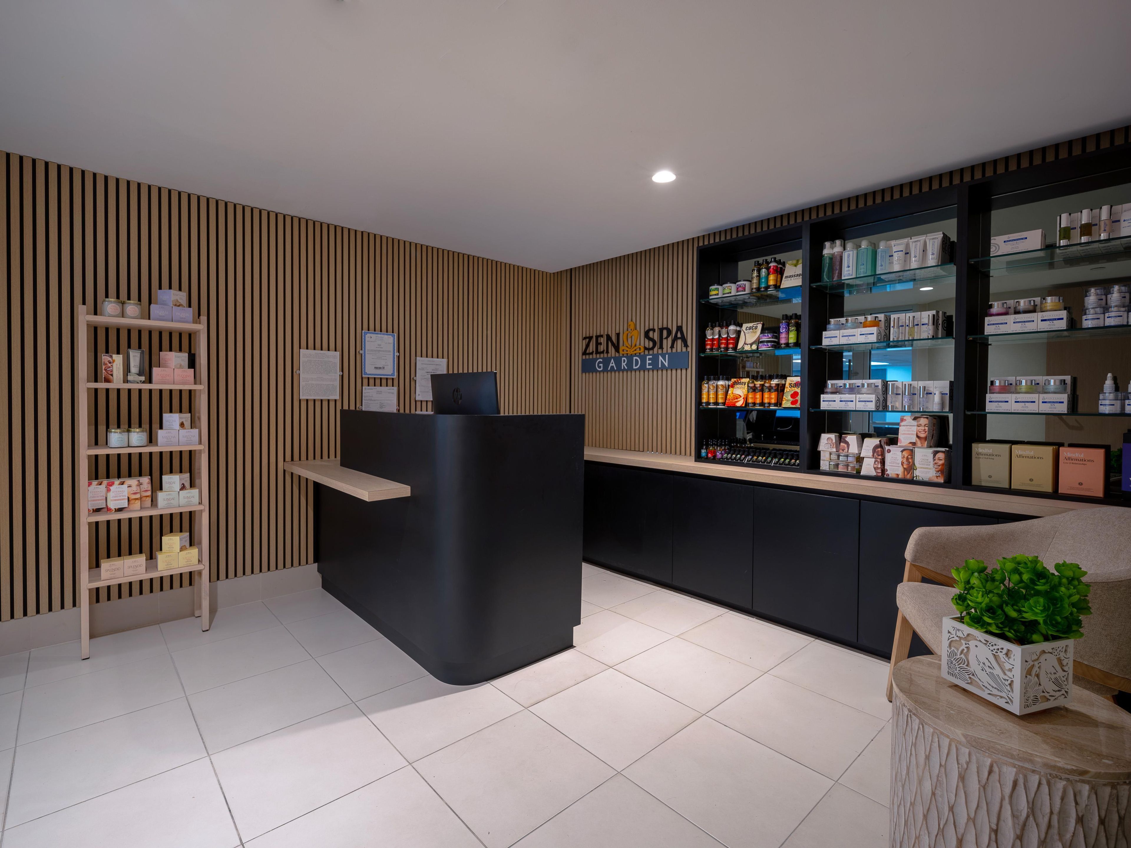 Un área de recepción con un revestimiento de listones de madera, un mostrador negro y estantes llenos de diversos productos.